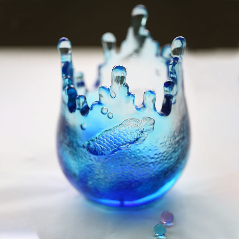 Украшения из синего стекла с выгравированными узорами рыб.