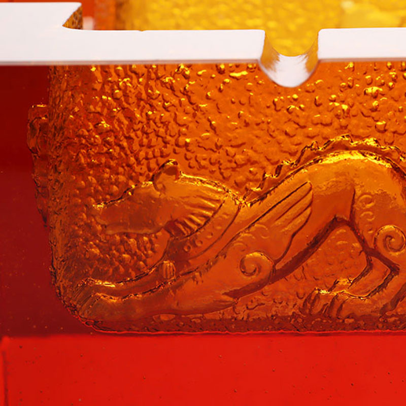 Пепельница из красного стекла с изысканным тиснением животных узоров.